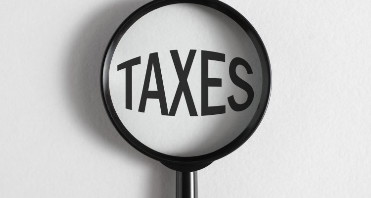 Tax increase, financial, economic concept. Magnifying glass focused on big word Taxes
